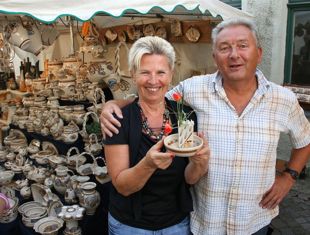 Marktstand der Heyde-Keramik mit bemaltem Steinzeug, davor das Gründerpaar mit einem Keramikstück