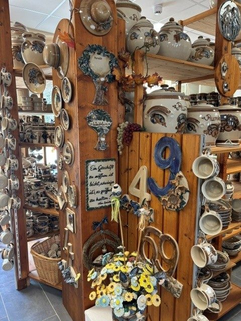 Holzsäule im Laden mit Türschildern, Hausnummern und Spruchtafeln aus Keramik